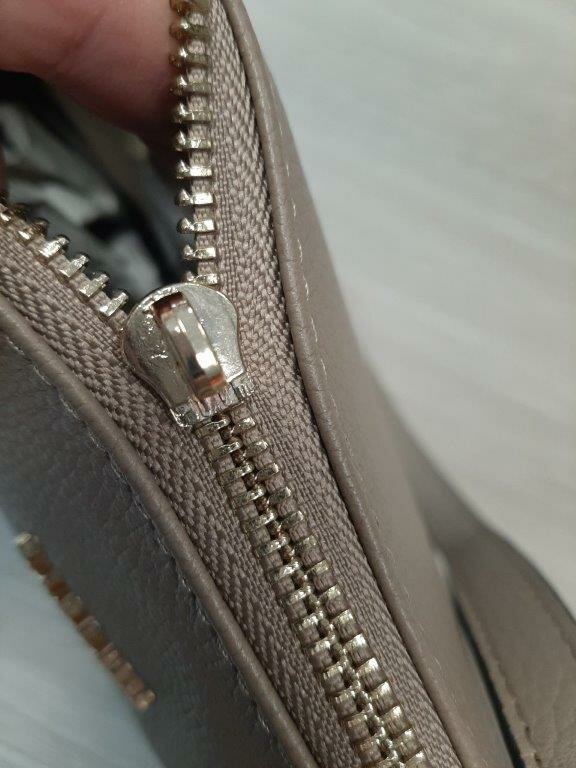 Nahaufnahme eines beschädigten Reißverschlusses einer Handtasche.